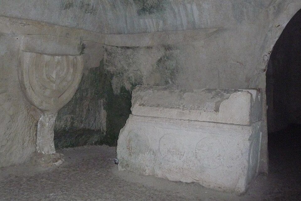 Carved menorah and stone sarcophagus inside the Beit Shearim catacombs