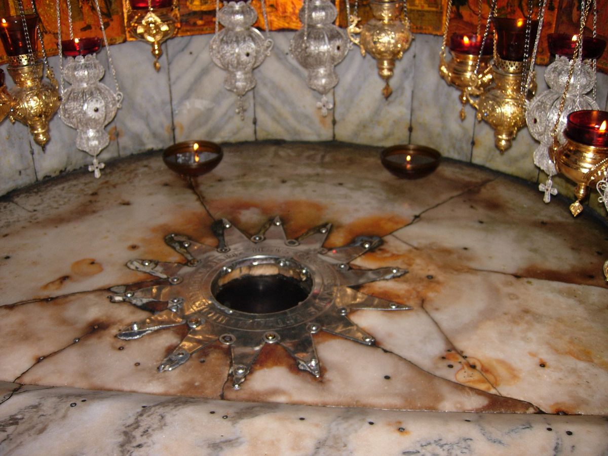 The star of Bethlehem in the Grotto of the Nativity with hanging oil lamps