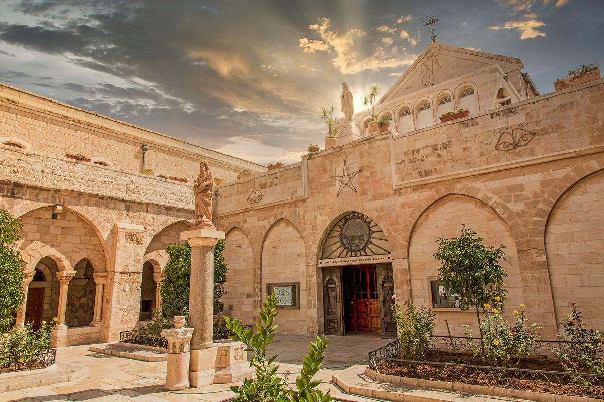 The courtyard of St Catherines Church in Bethlehem with arches and the statue of St Catherine
