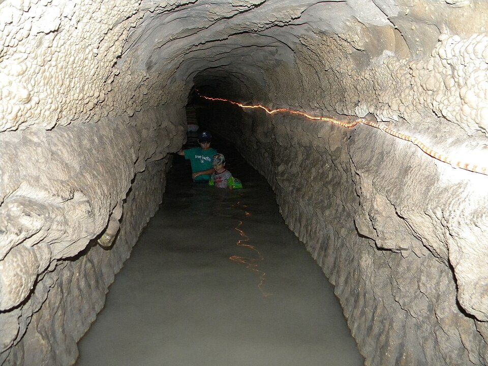 Inside the Mei Kedem ancient water tunnel at Park Alona with visitors wading through the water