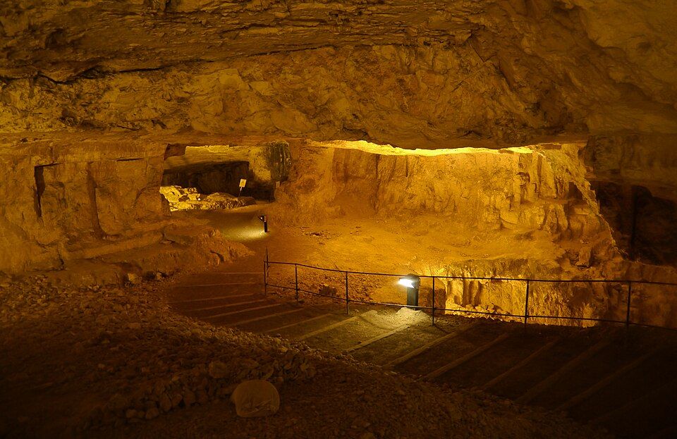 The vast interior of Zedekiahs Cave with stairs and illuminated limestone walls